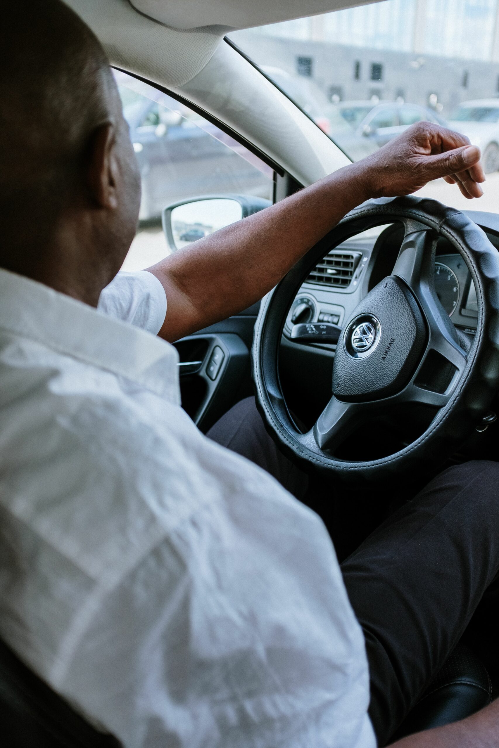 Home A man driving a vehicle, highlighting the steering wheel and car interior.
