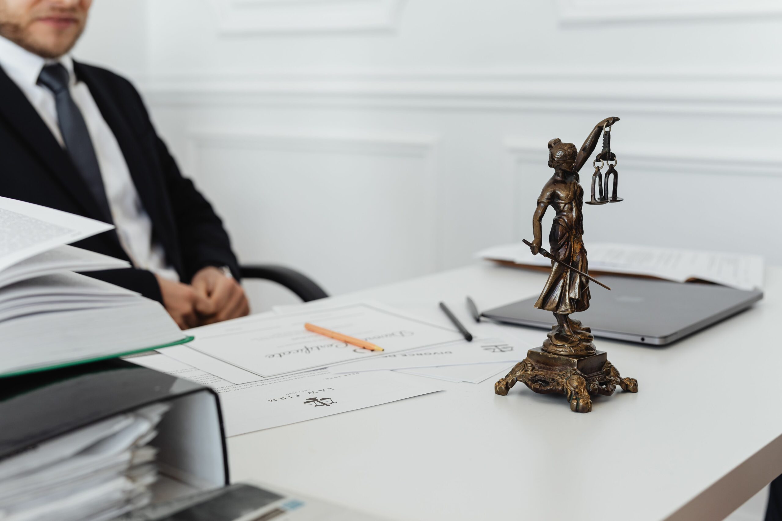 A legal professional's workspace featuring Lady Justice statue, documents, and a laptop.